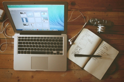 Laptop, Notizbuch und Kamera von oben