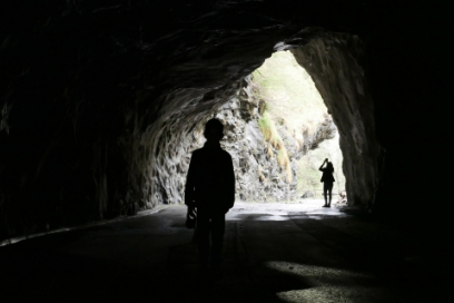 Zu Fuss durchs "Verlorna Loch" Umrisse zweier Personen in einem Tunnell