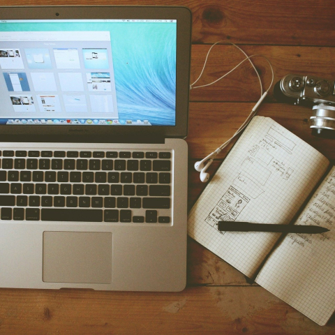 Laptop, Notizbuch und Kamera von oben