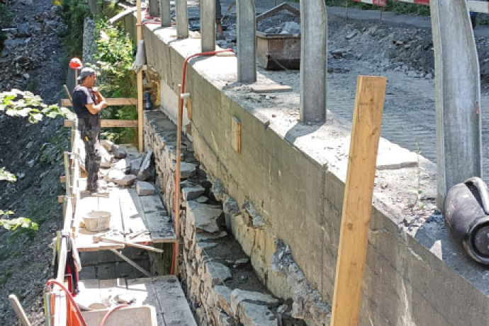 Profis am Werk: Sanierungsarbeiten 2023 im Verlorna Loch. Baustelle am Rand einer steil abfallenden Bergstrasse